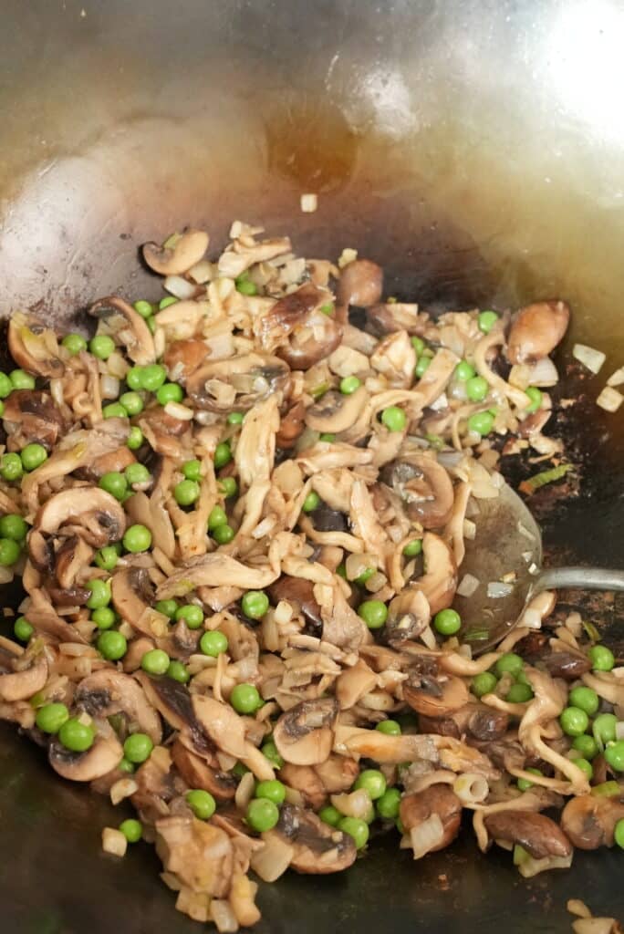 mushrooms and peas cooking in a wok