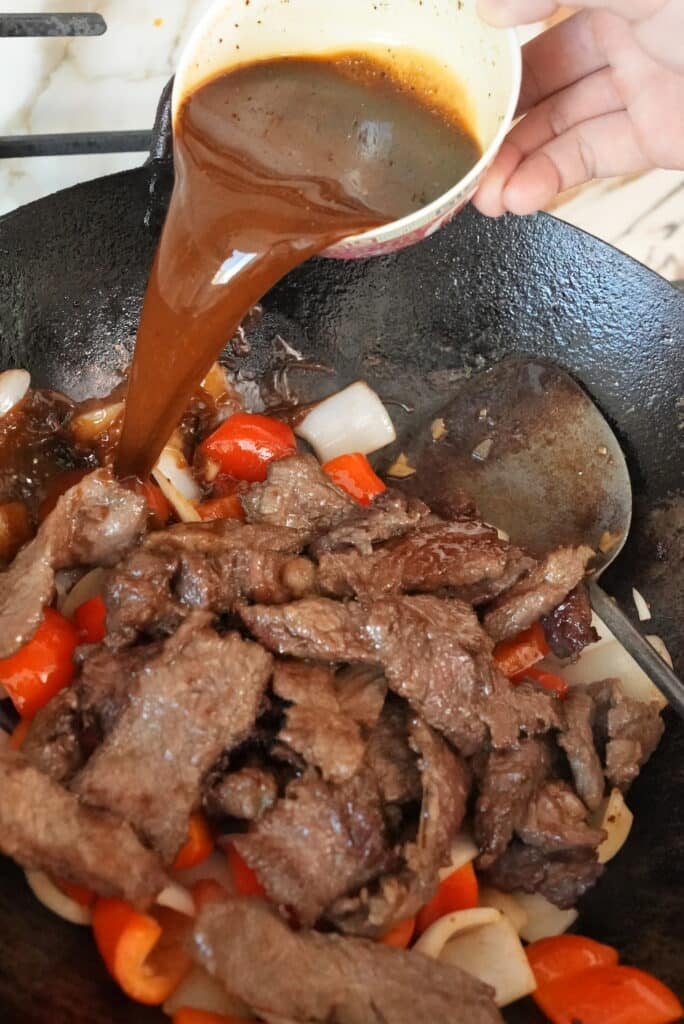 adding sauce to the wok for black pepper beef