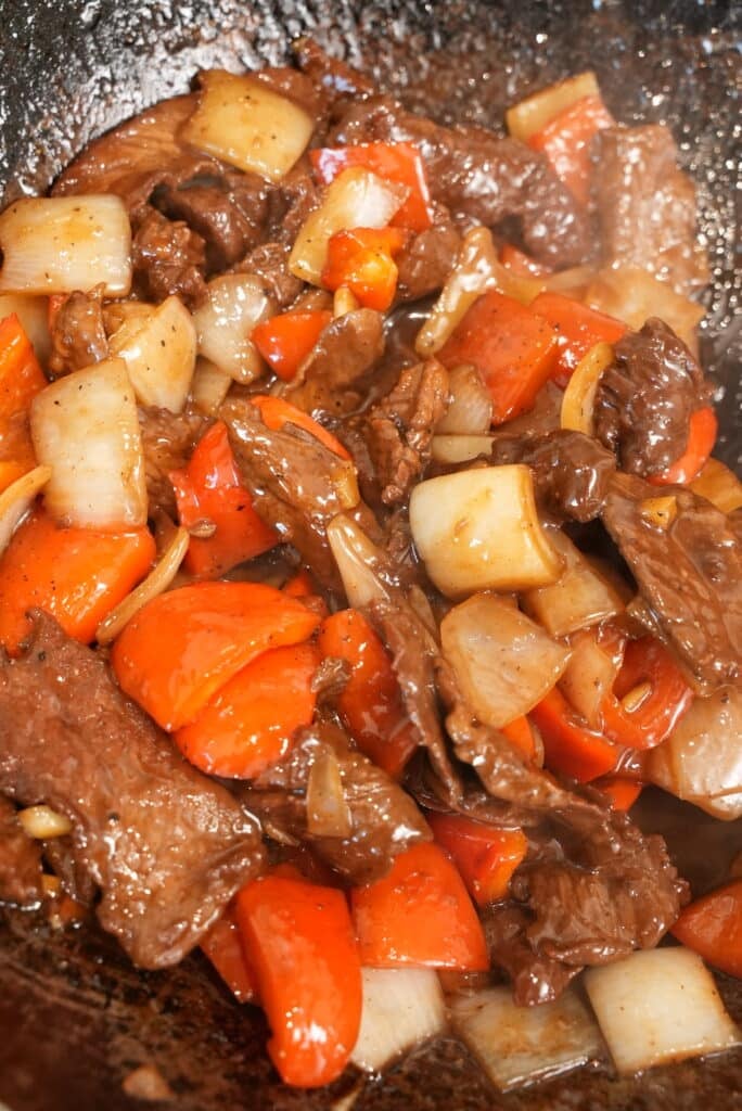 close up of black pepper beef in a wok