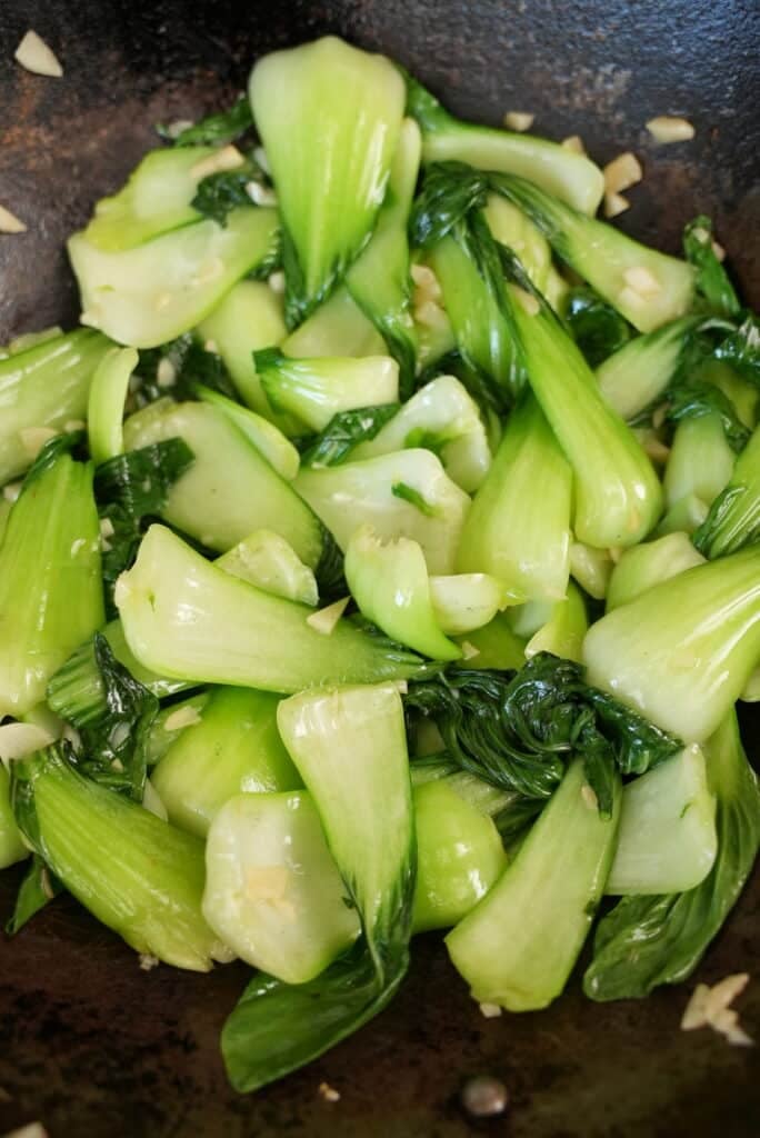 Bok choy cooking in a wok.