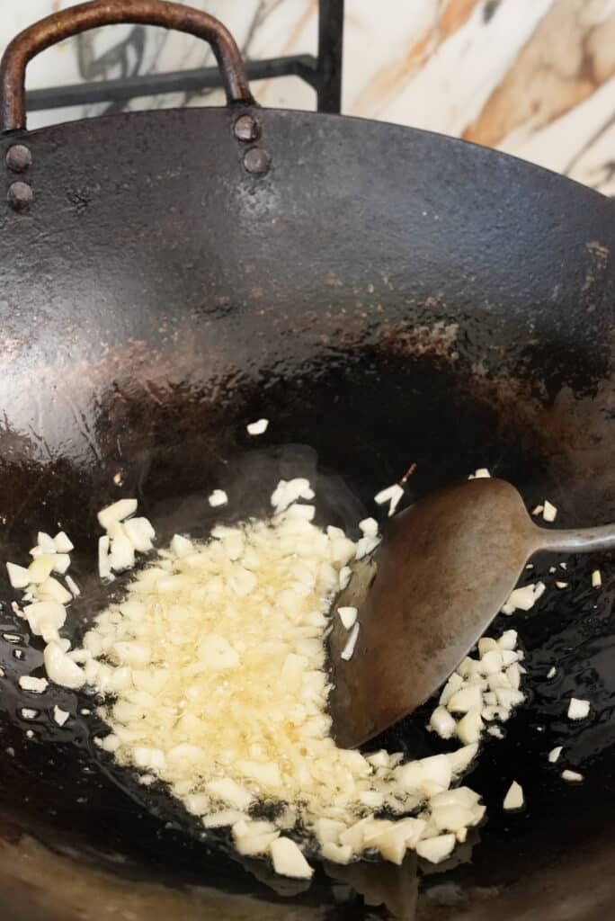 Frying garlic in a wok with neutral oil.
