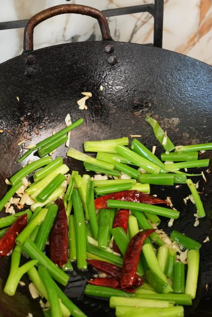 adding scallions and chili to wok