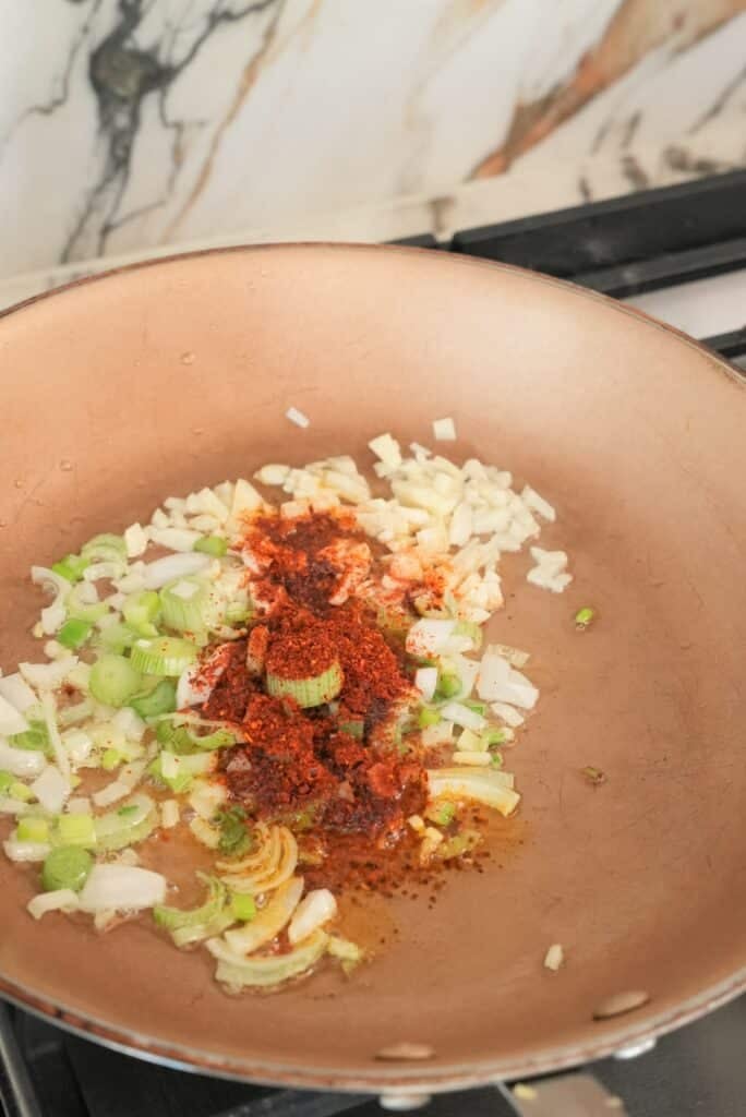 Frying garlic ginger and chili flakes in a pan.