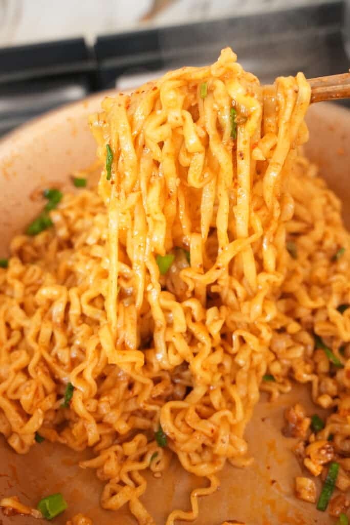 Spicy Garlic Ramen in pan pulled with chopsticks.