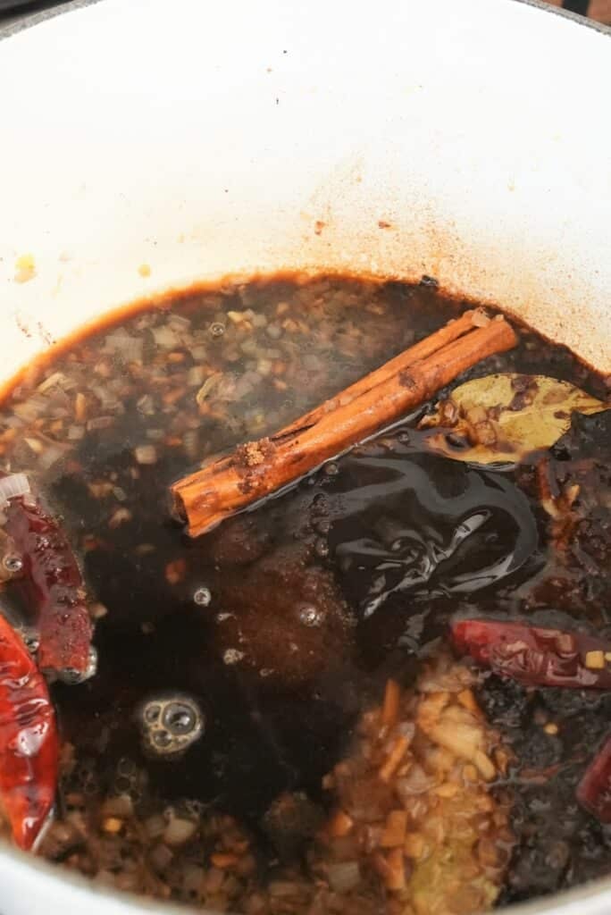 adding sauce to a pot for braising