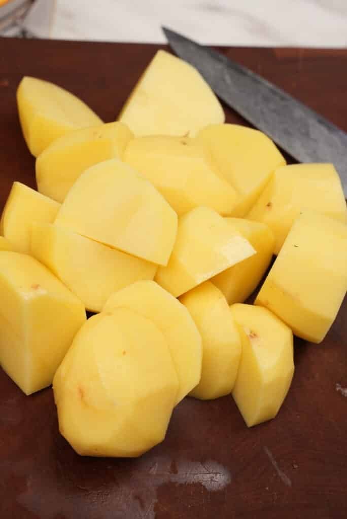 Diced raw yellow potatoes on a cutting board.