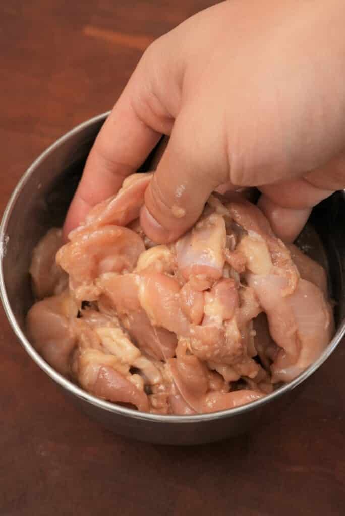 Marinated chicken thigh in a bowl.