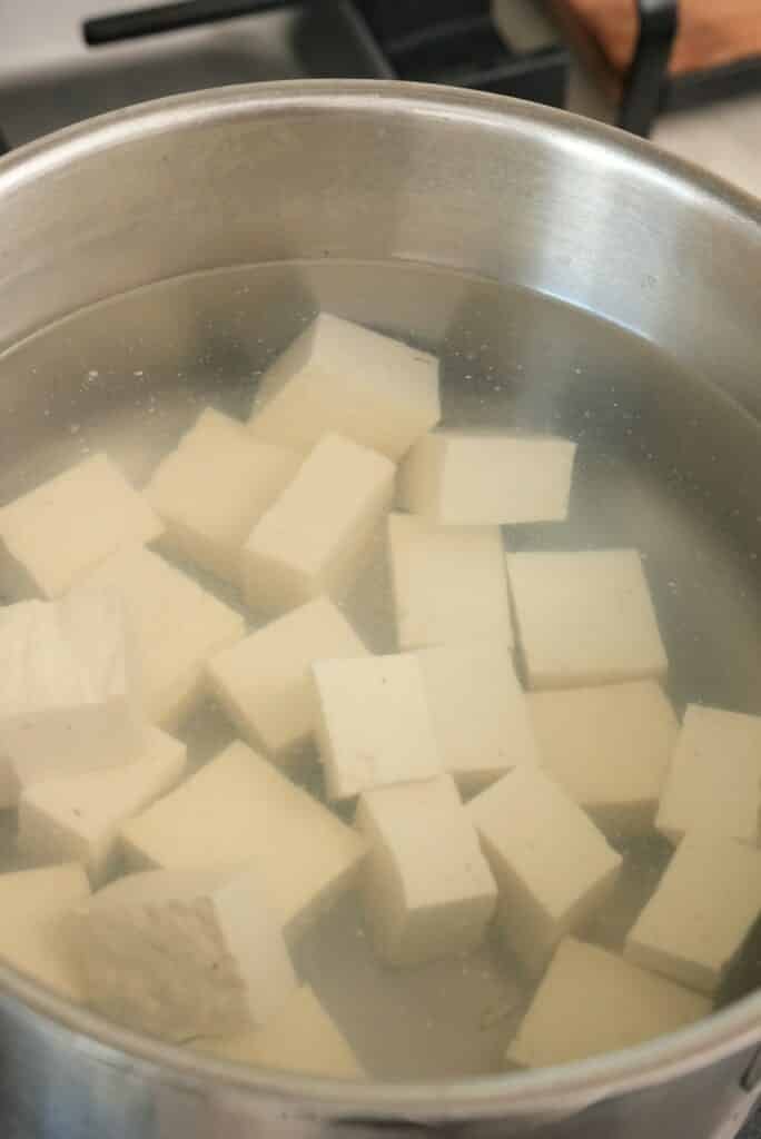 Cubed tofu blanching in salted water.