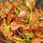 Mongolian Beef cooked in a wok with scallions, chili peppers, and beef.