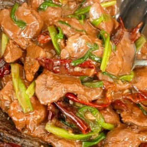 Mongolian Beef cooked in a wok with scallions, chili peppers, and beef.