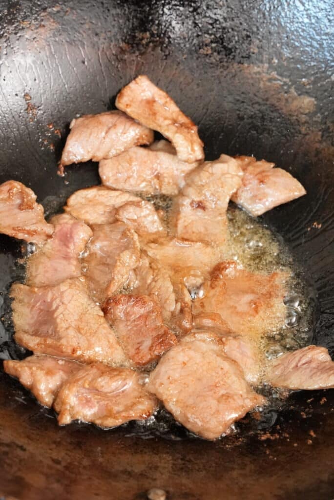 Frying beef in oil in a wok.