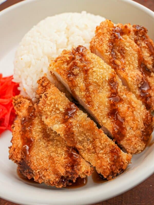 Crispy Air Fryer Chicken Katsu in a bowl with rice, tonkatsu sauce, and pickled radish.