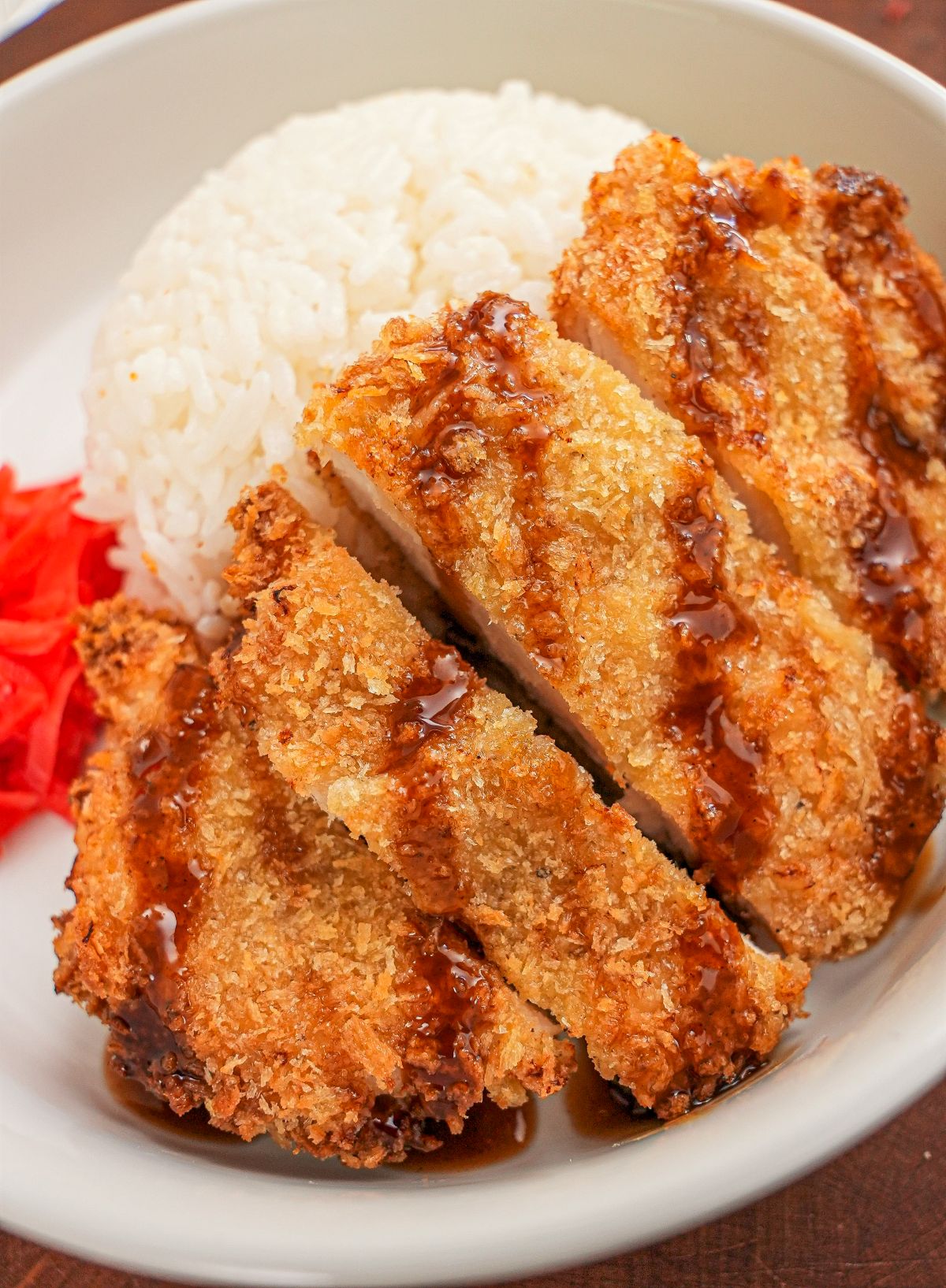 Crispy Air Fryer Chicken Katsu in a bowl with rice, tonkatsu sauce, and pickled radish.
