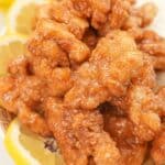 A plate of Chinese Lemon Chicken on a plate with lemon slices and rice.