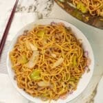 Copycat Panda Express Chow Mein in a bowl next to chopsticks and a wok with more chow mein.