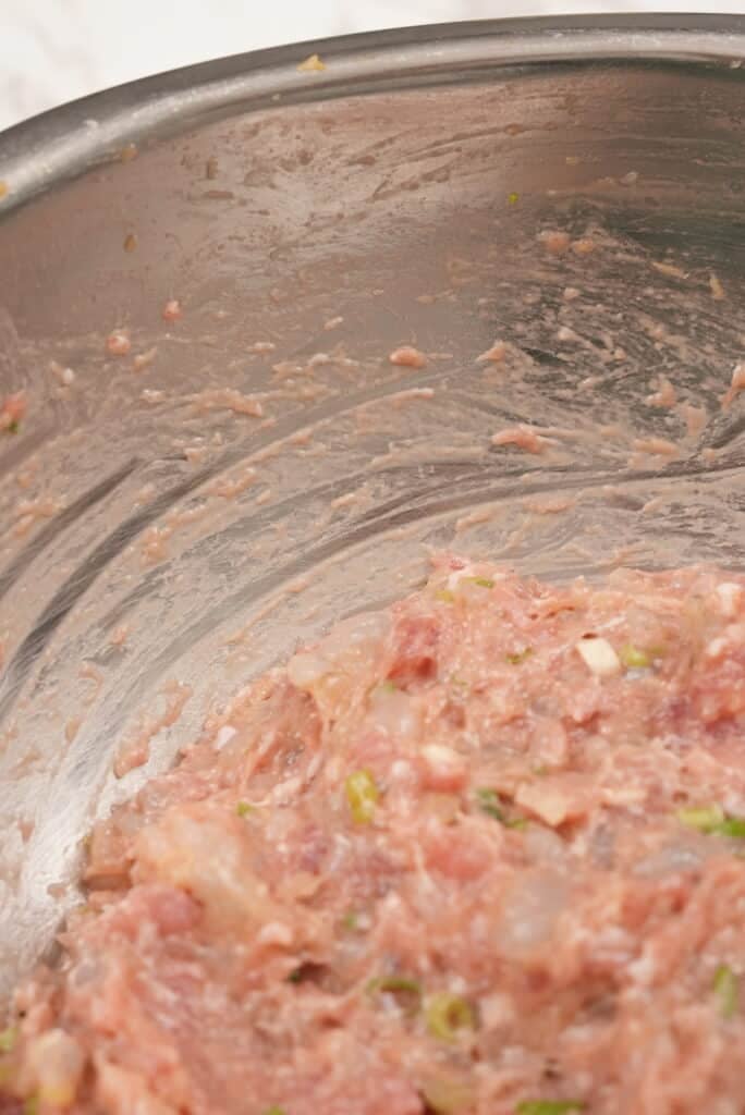 Close up of pork and shrimp wonton filling to show streaks on the bowl.