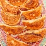 Pork and Chive dumplings that have been pan fried plated on a vintage Chinese ceramic plate.