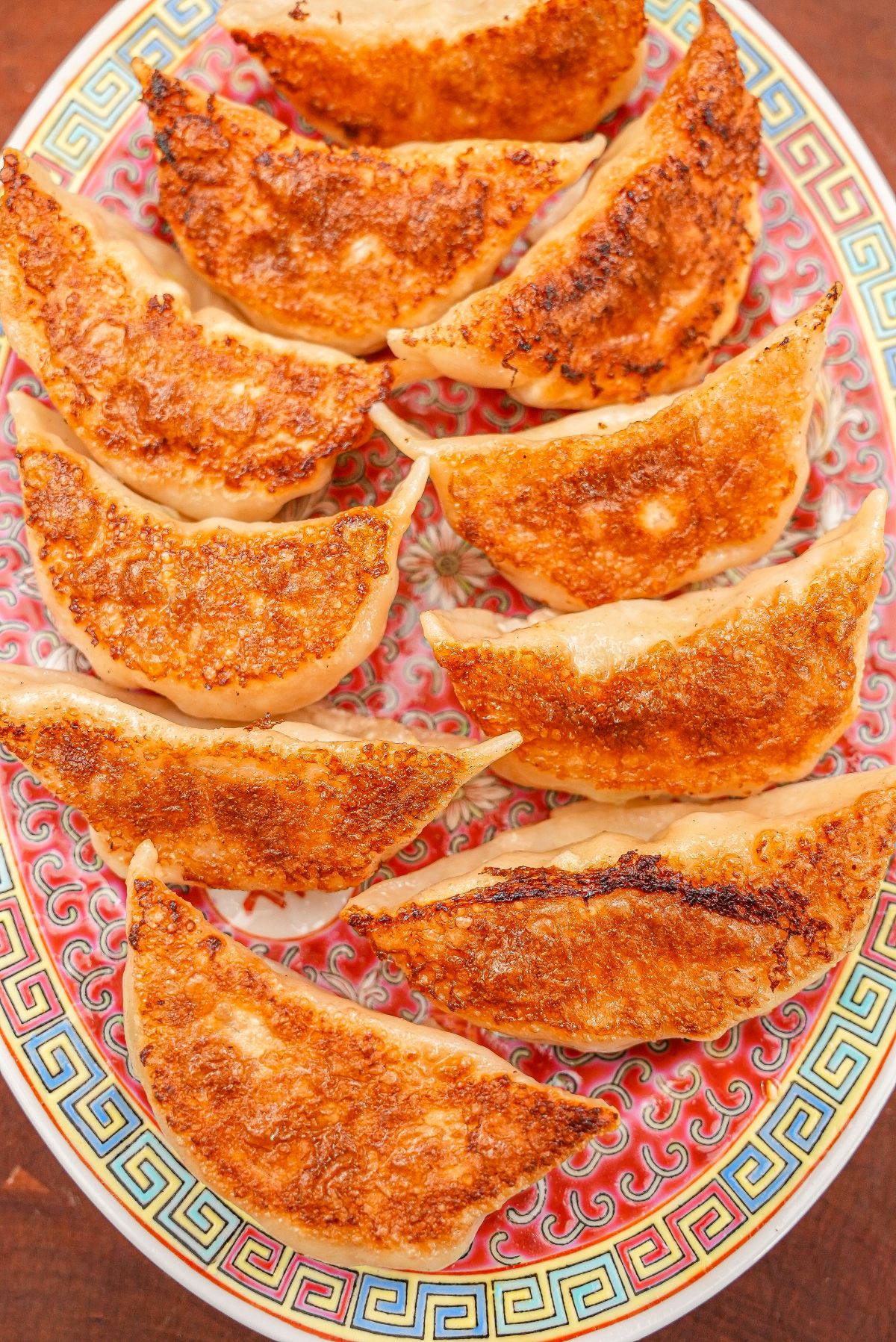 Pork and Chive dumplings that have been pan fried plated on a vintage Chinese ceramic plate.
