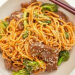 Beef and Broccoli Noodles in a bowl with chopsticks.