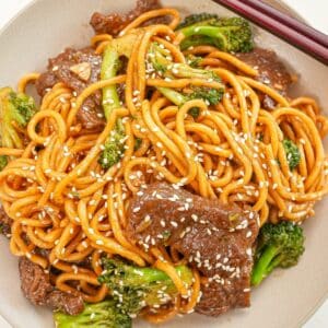 Beef and Broccoli Noodles in a bowl with chopsticks.