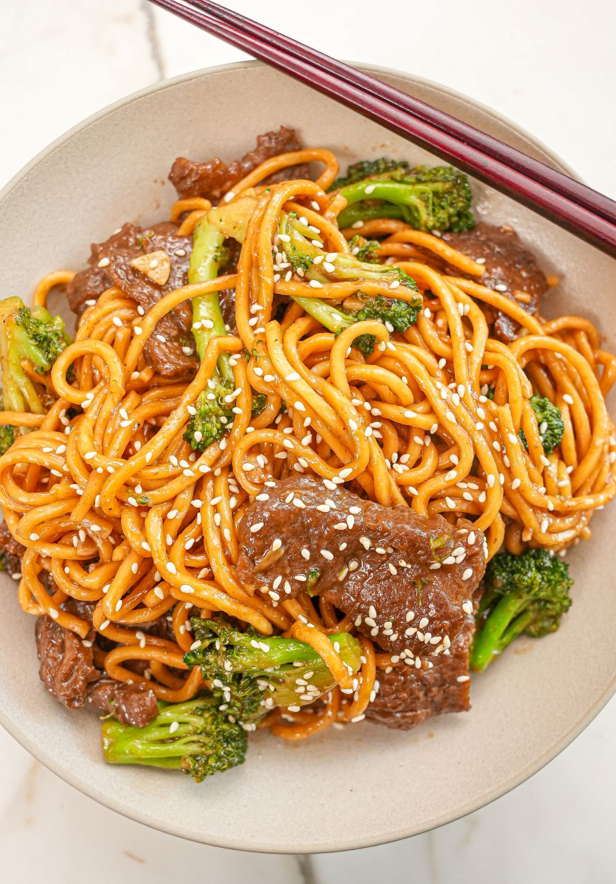 Beef and Broccoli Noodles in a bowl with chopsticks.
