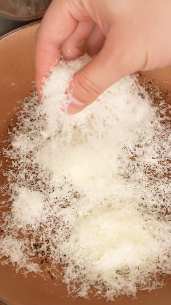 Adding cheese to black pepper in a pan