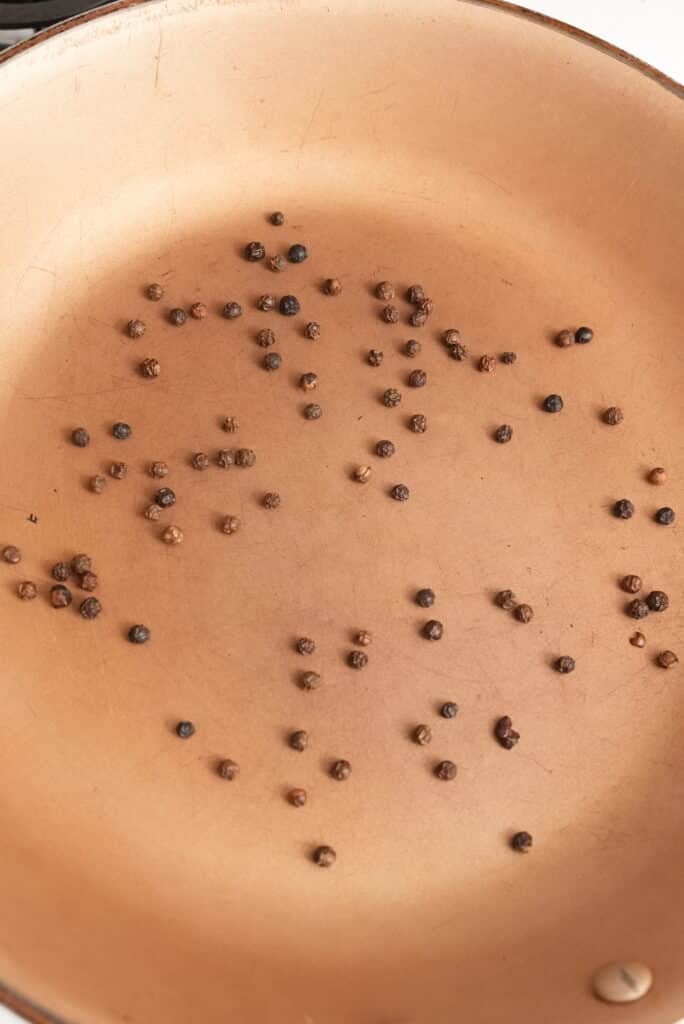 black peppercorns toasting in a pan