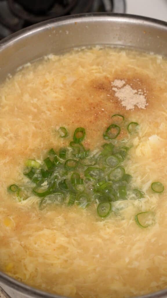 Seasoning chicken corn egg drop soup with white pepper and scallions