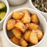 Korean braised potatoes in a bowl next to other bowls of banchan or Korean side dishes.