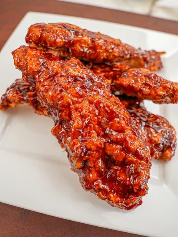 Korean Fried Chicken Tenders on a plate tossed in a spicy gochujang sauce.