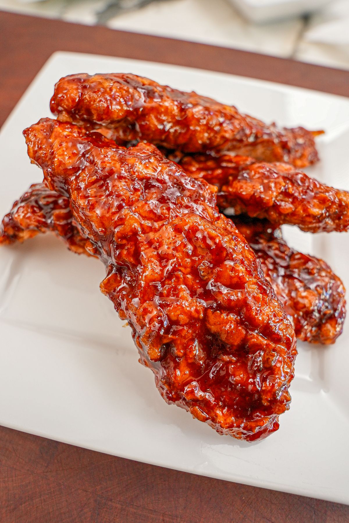 Korean Fried Chicken Tenders on a plate tossed in a spicy gochujang sauce.