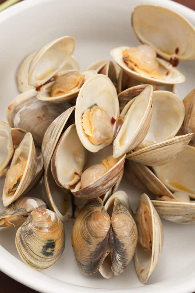 Steamed clams in their shells open in a bowl.
