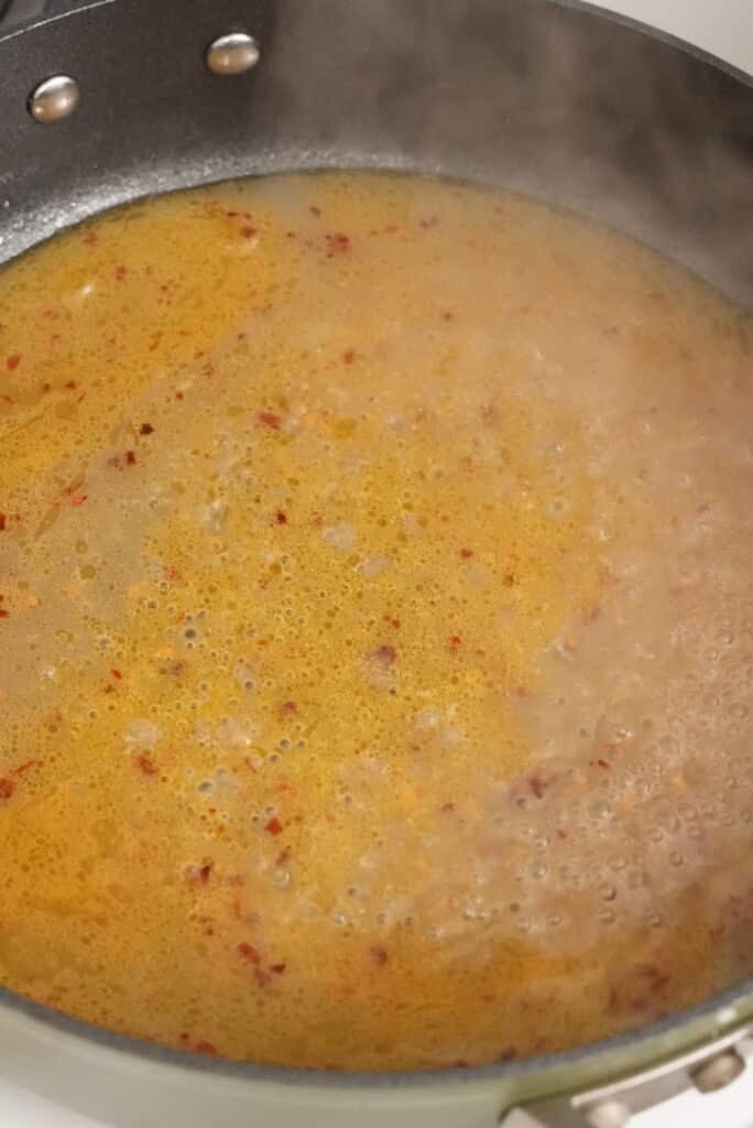 reducing the clam sauce in a pan
