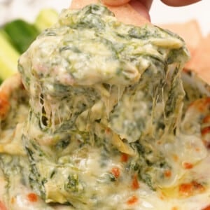 Close up of Spinach Artichoke dip with a tortilla chip