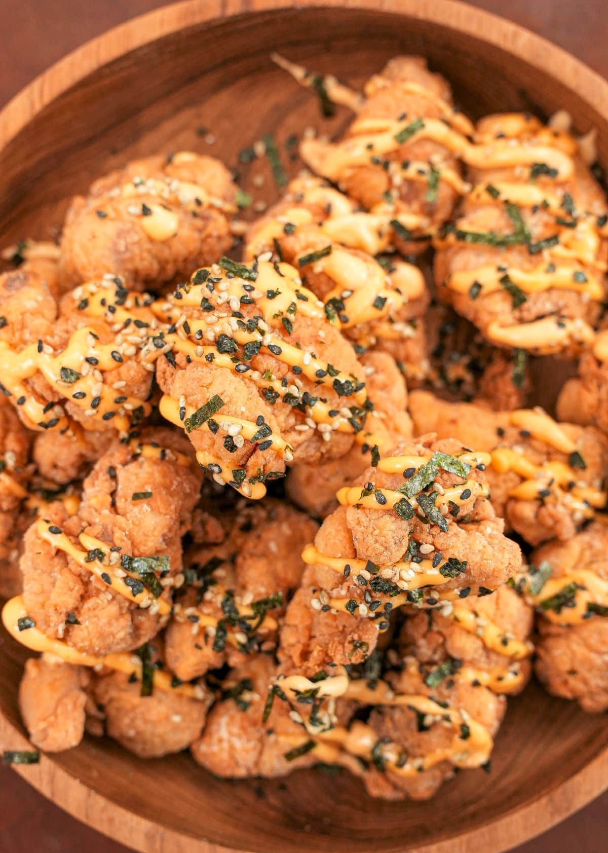 Crispy Mochiko Chicken in a wooden bowl with furikake and a spicy mayo sauce.
