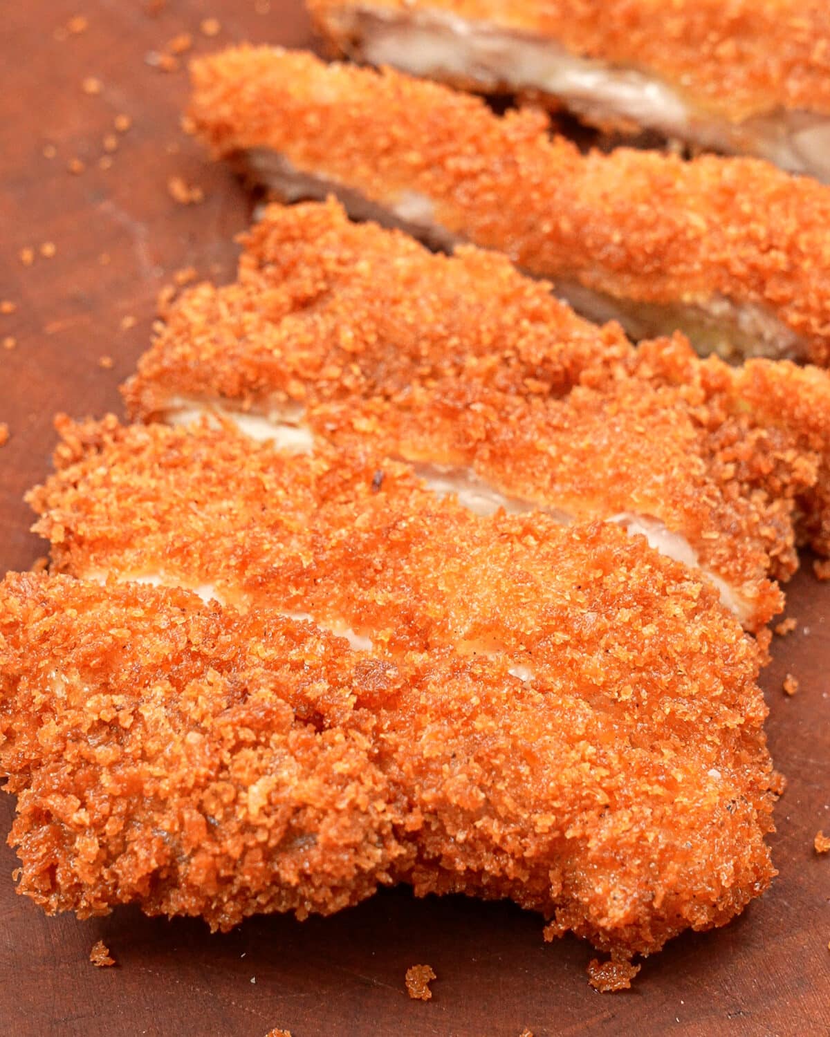 A crispy chicken katsu cut into strips on a cutting board.