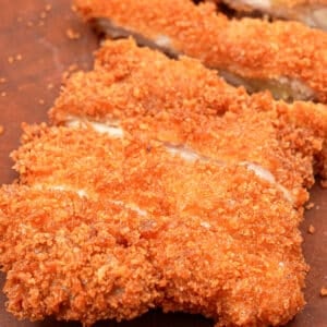 A crispy chicken katsu cut into strips on a cutting board.