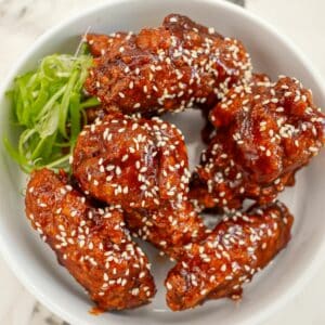Korean Gochujang Honey wings in a bowl with scallions.