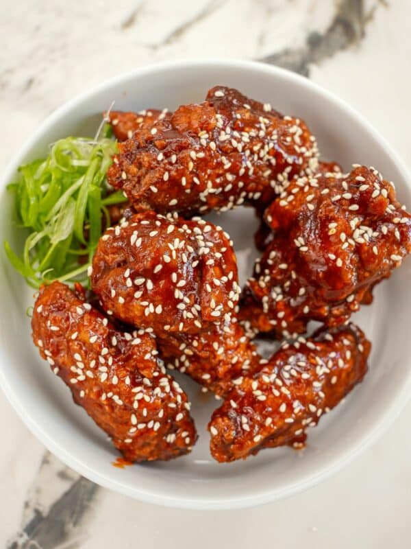 Korean Gochujang Honey wings in a bowl with scallions.