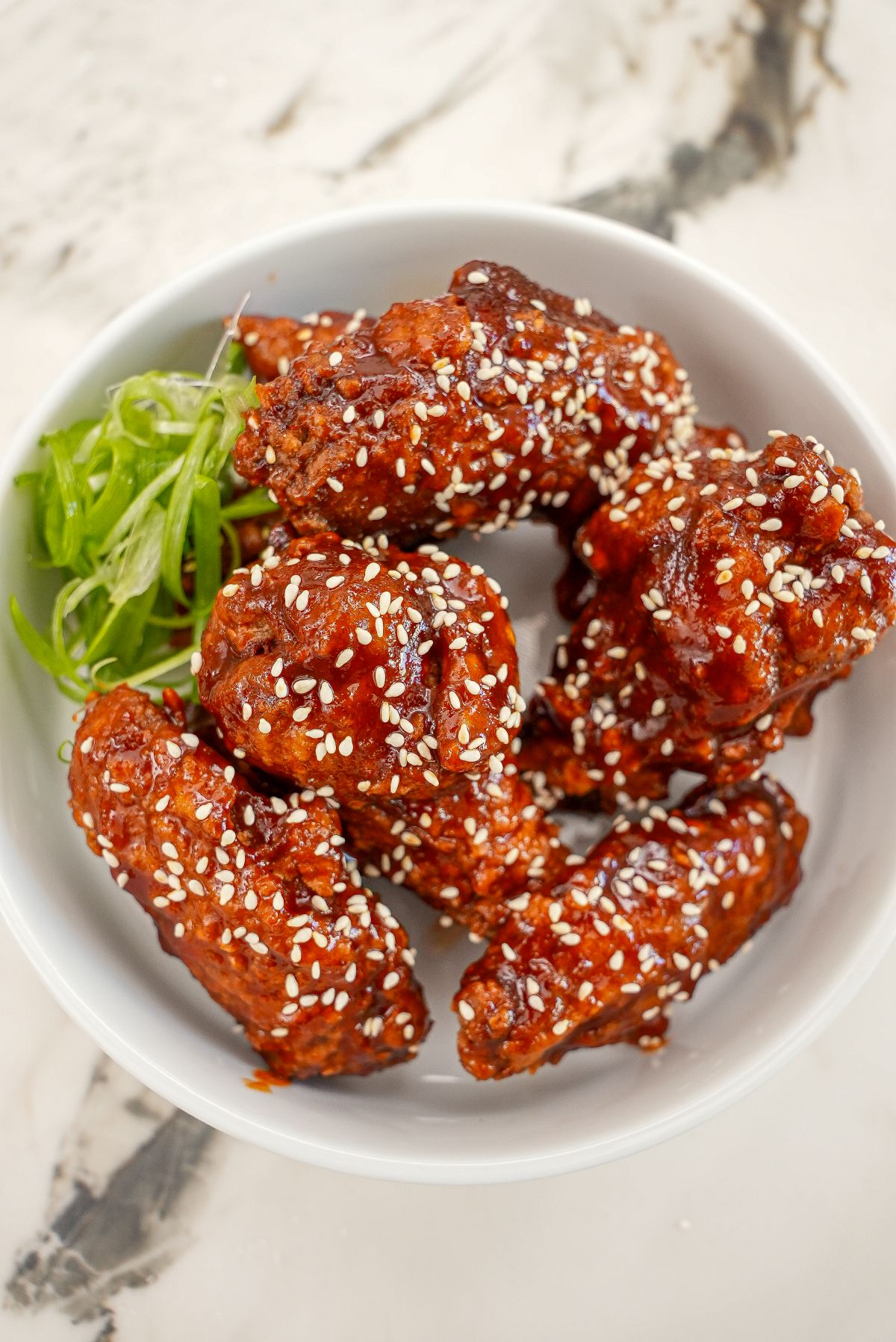 Korean Gochujang Honey wings in a bowl with scallions.