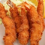 A bowl of fried panko shrimp with shredded cabbage and lemon.
