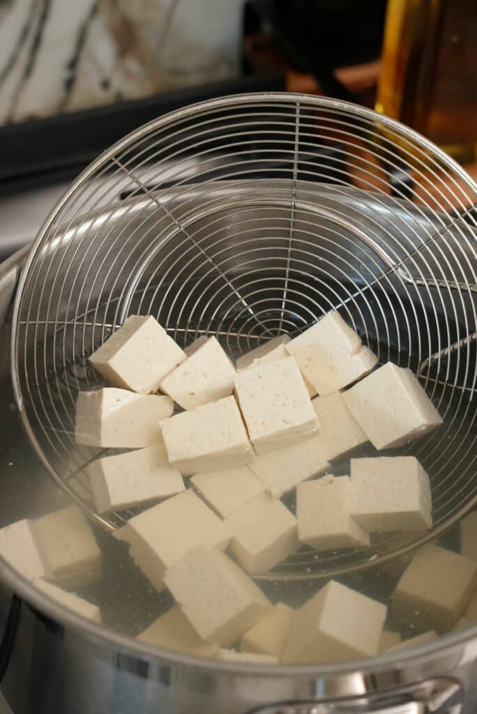 Blanching tofu in a pot of hot water.