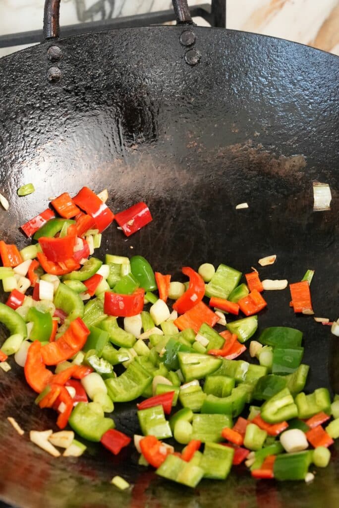 Red and green chilis sauteing in a wok