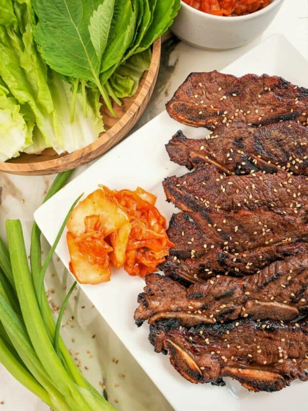 A plate of Korean marinated short ribs (Galbi) on a plate with kimchi and lettuce.