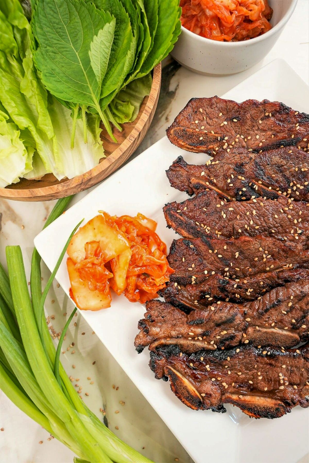 A plate of Korean marinated short ribs (Galbi) on a plate with kimchi and lettuce.