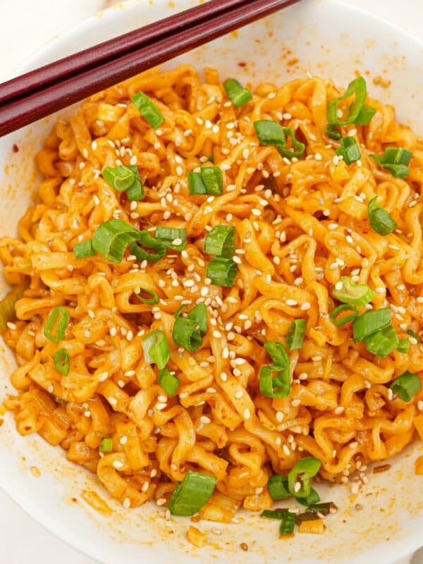 Spicy garlic ramen in a bowl with scallions, sesame seeds and a pair of chopsticks.