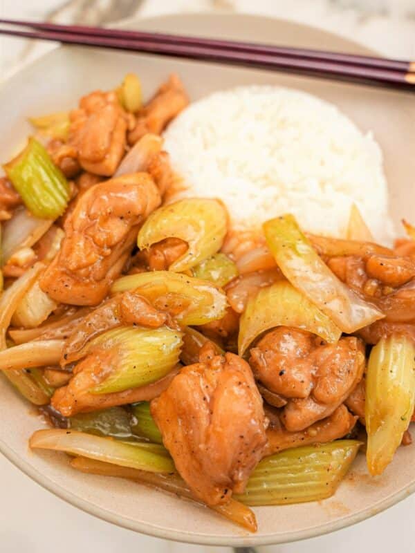 Black Pepper Chicken in a bowl with rice and chopsticks.