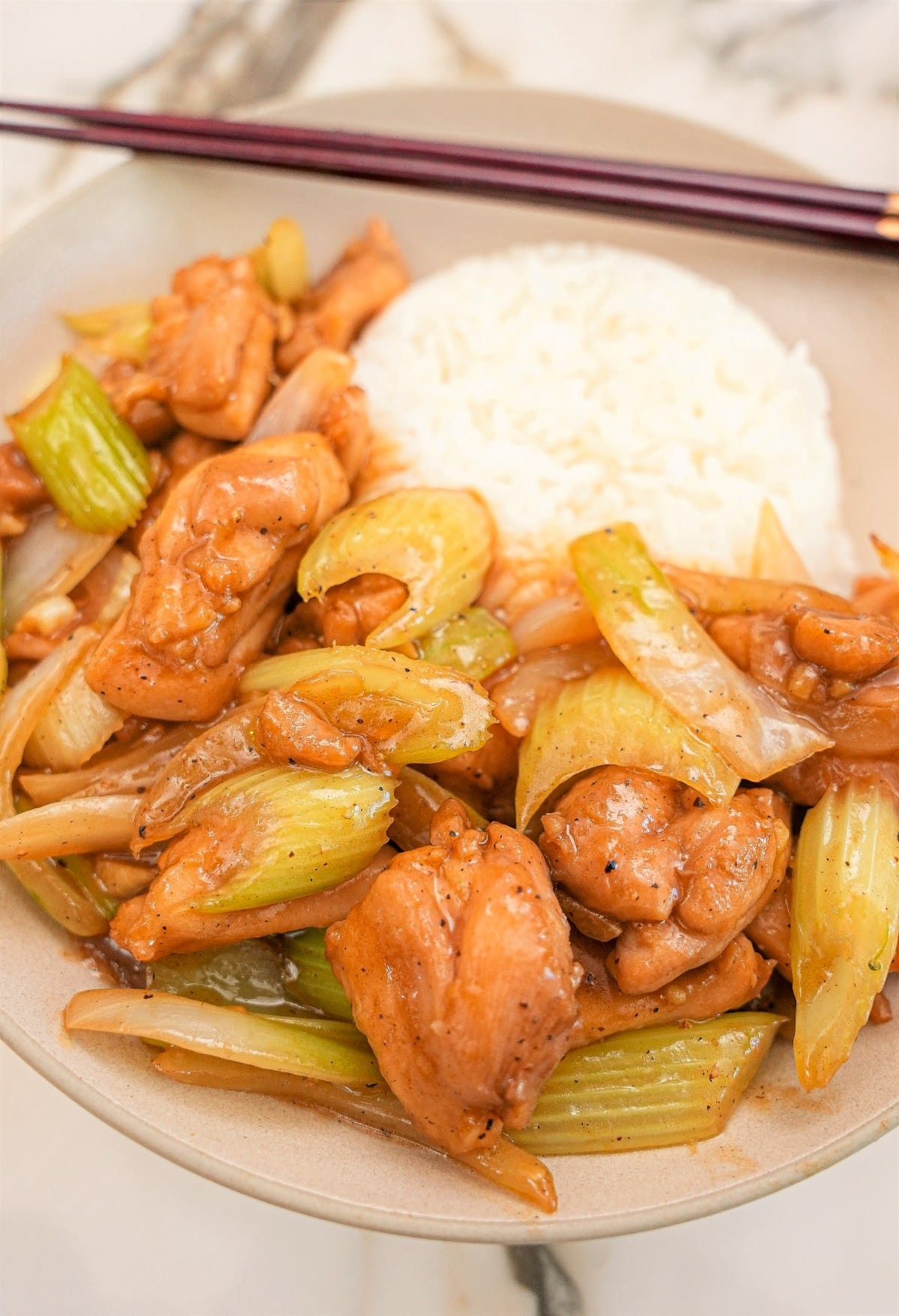 Black Pepper Chicken in a bowl with rice and chopsticks.