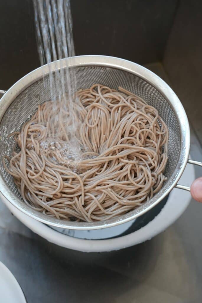 Rinsing soba noodles under cold water