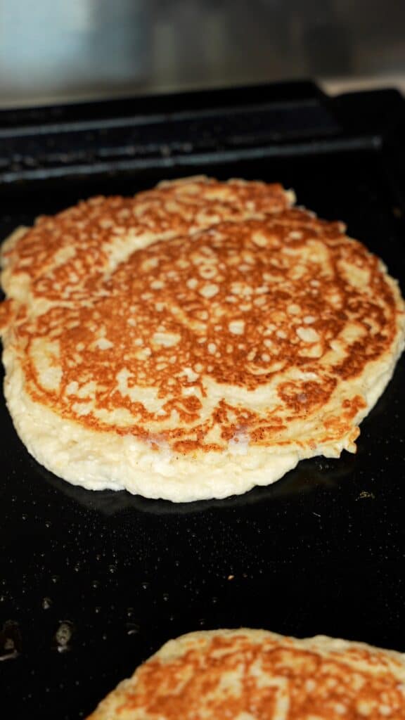 lemon ricotta pancakes cooking on a griddle